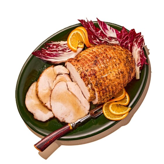 Sliced roasted turkey breast roast with orange slices and radicchio, festive holiday meal centerpiece.